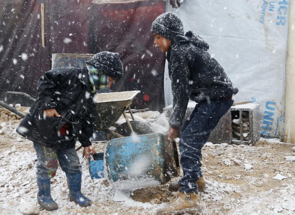 Syrian refugee children carry a cooking gas canister outside their tent during a winter storm in Zahle town, in the Bekaa valley December 11, 2013. The worst of winter is yet to come for 2.2 million refugees living outside Syria and millions more displaced inside the country. A storm named Alexa is sweeping across Syria and Lebanon, bringing with it high winds and freezing temperatures - and marking the beginning of the third winter since the Syrian conflict began in March 2011. In the tented settlement a few kilometres (miles) from the border in Lebanon's Bekaa Valley, more than 1,000 people live in rudimentary shelters. REUTERS/Mohamed Azakir (LEBANON - Tags: POLITICS CIVIL UNREST CONFLICT SOCIETY IMMIGRATION ENVIRONMENT ENERGY TPX IMAGES OF THE DAY)