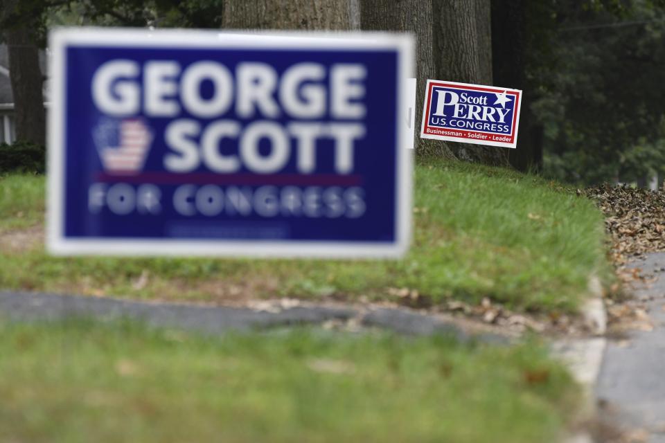 Campaign signs for Republican U.S. Rep. Scott Perry of Pennsylvania and Democratic challenger George Scott as seen on a neighborhood street in the district, Saturday, Oct. 6, 2018 in Camp Hill, Pa. A court-ordered redrawing of Pennsylvania's House districts has forced several Republican congressmen, including Perry, into more competitive seats and helped establish Pennsylvania as a key state for Democrats aiming to recapture the House majority. (AP Photo/Marc Levy)