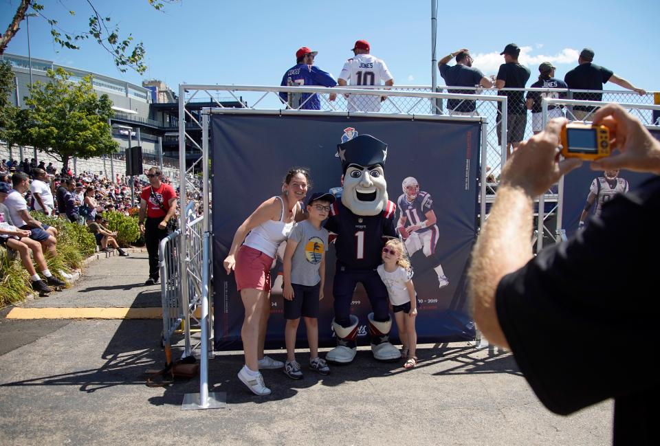 New England Patriots fans Celeste Van Daele, her son Mathieu, and daughter Charlotte, visiting from Belgium, pose for a photo with Pat Patriot during training camp at the NFL football team's practice facility in Foxborough, Mass. on July 30, 2022.