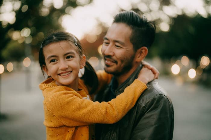 A father holding his daughter while they are outdoors