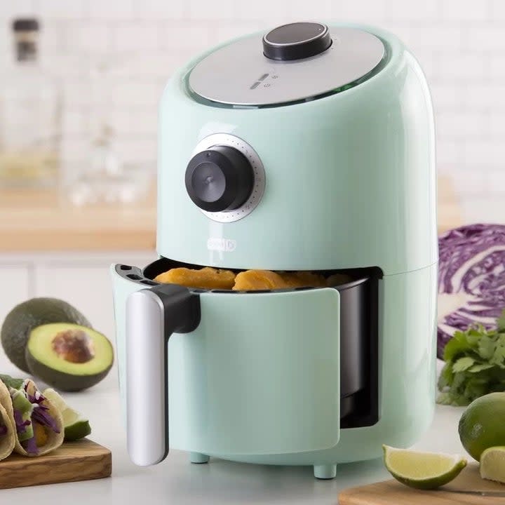 Light blue air fryer with food in it