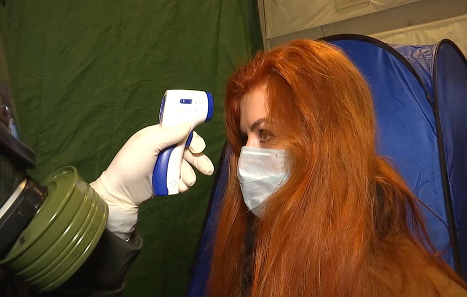 RUSSIA - FEBRUARY 5, 2020: Measuring the temperature of a passenger of an Ilyushin Il-76 plane travelling from the Chinese city of Wuhan. Two Ilyushin Il-76 planes of the Russian Aerospace Forces brought 144 Russian citizens to the Tyumen Region. The passengers are sent for quarantine to the Gradostroitel Treatment and Rehabilitation Center. Video screen grab. Russian Defense Ministry/TASS (Photo by Russian Defense Ministry\TASS via Getty Images)