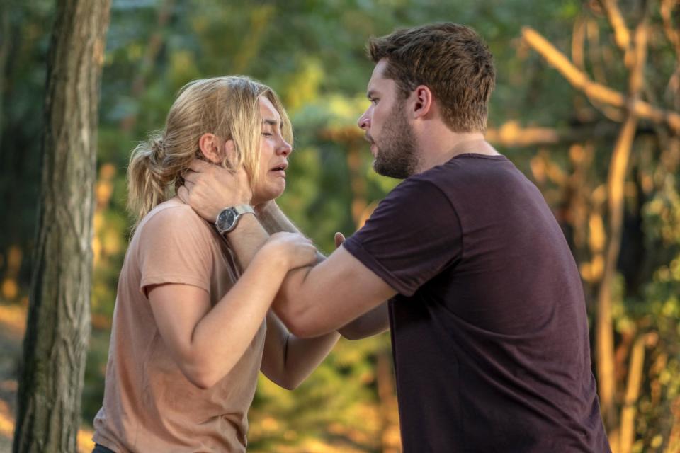 A crying woman’s face is held by her boyfriend in the woods