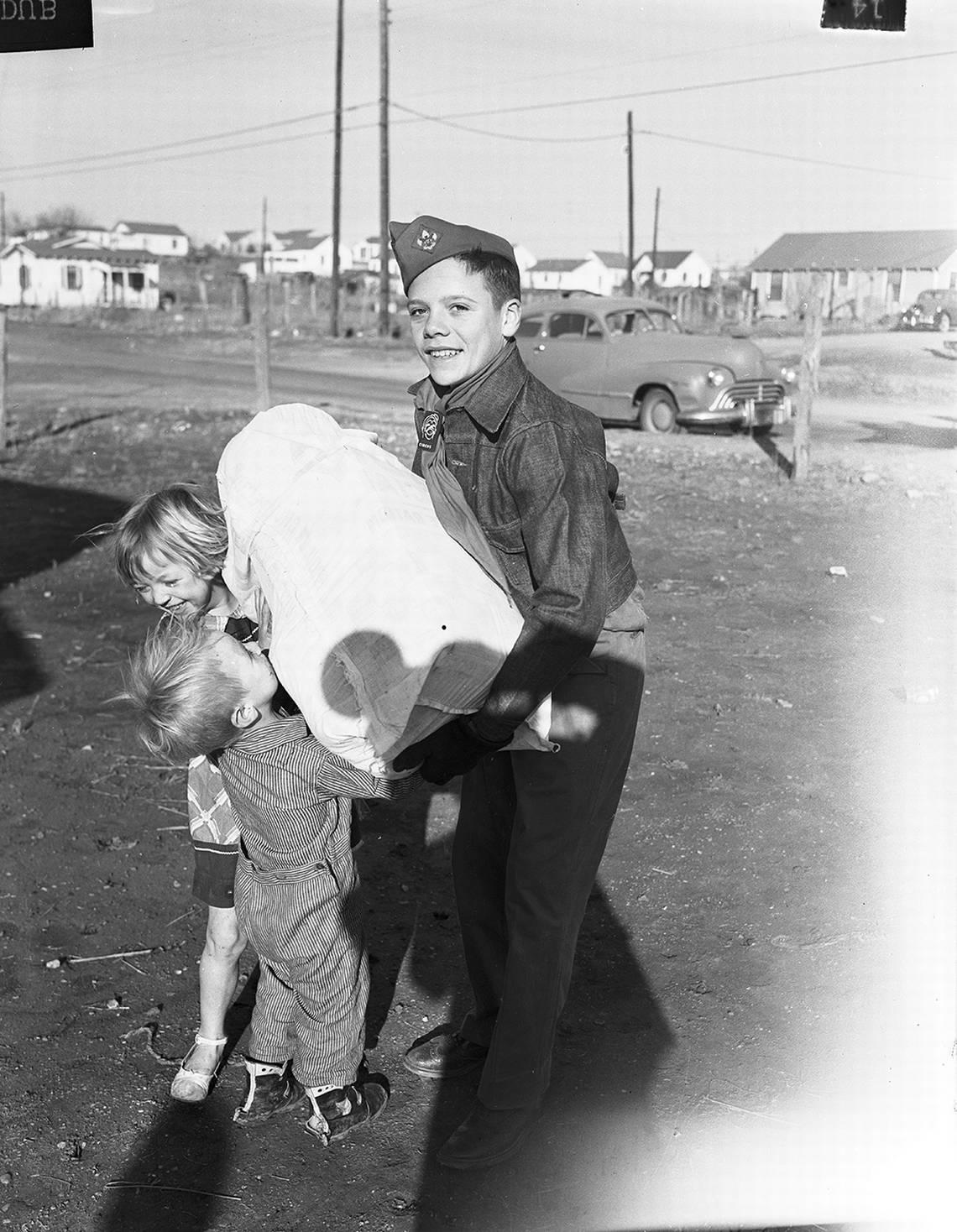 Dec. 23, 1952: The Goodfellows are filling the arms of children such as these. Here Kenneth Fallin, a Boy Scout helping with the Goodfellow deliveries, has to assist with this heavy sack. Its weight, however, meant it will be a Merry Christmas for these little children. Fort Worth Star-Telegram archive/UT Arlington Special Collections