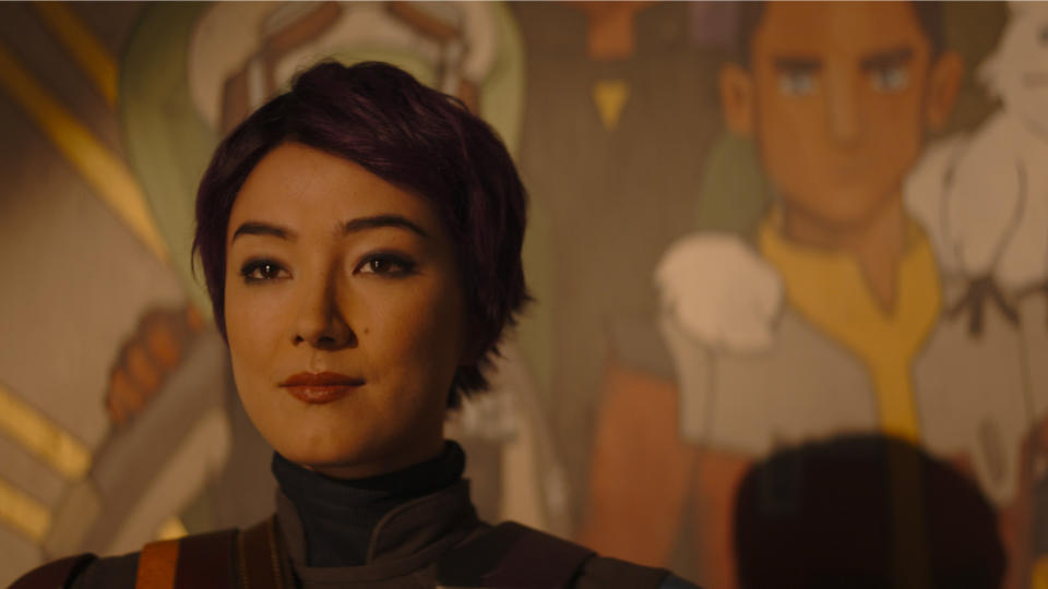 A short-haired Sabine Wren standing in front of the mural of Ezra Bridger in Ahsoka episode 2