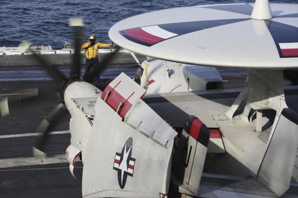 In this Monday, March 20, 2017 photograph, crew reposition an E-2C Hawkeye on the USS George H.W. Bush as it travels toward the Strait of Hormuz. The arrival of the nuclear-powered aircraft carrier to the Persian Gulf marks the first such deployment under new U.S. President Donald Trump. (AP Photo/Jon Gambrell)