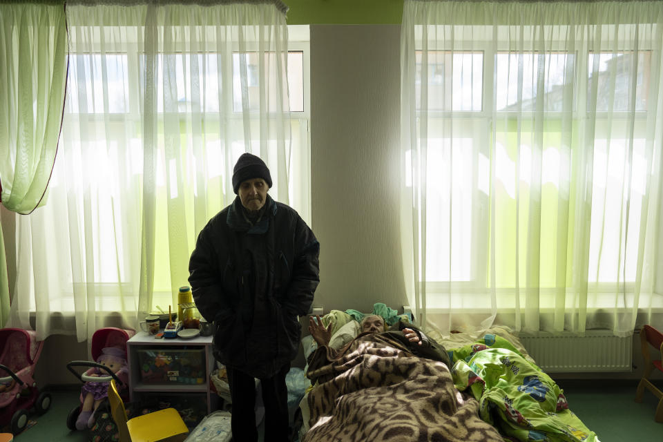 FILE - Nina Kirinchenko, 90, greets journalists next to her husband in part of a building that was converted as housing for 400 people, since apartments were used by Russian soldiers during the occupation of Bucha, on the outskirts of Kyiv, Ukraine, April 4, 2022. (AP Photo/Rodrigo Abd, File)