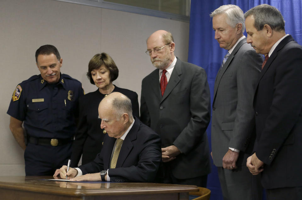 FILE -- In this Jan. 17, 2014 file photo Gov. Jerry Brown, seated, signs a drought proclamation while declaring a state of emergency in San Francisco. Brown was governor the last time California had a drought of epic proportions, in 1975-76 and now is pushing a controversial $25 billion plan to build twin tunnels to ship water from the Sacramento-San Joaquin River Delta to farmland and cities further south. (AP Photo/Jeff Chiu, file)