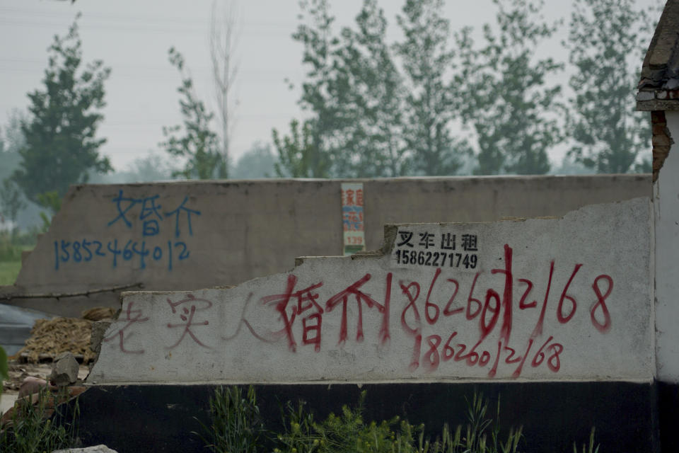 In this April 29, 2019 photo, graffiti advertising a marriage agent is spray-painted on the wall of a warehouse in Pei County in eastern China's Jiangsu province. In China, demand for foreign brides has mounted, a legacy of the one-child policy that skewed the country’s gender balance toward males. In recent years, tens of thousands of Chinese workers have gone to Pakistan to work on China's Belt and Road construction projects, and some returned to China with Pakistani wives. (AP Photo/Dake Kang)