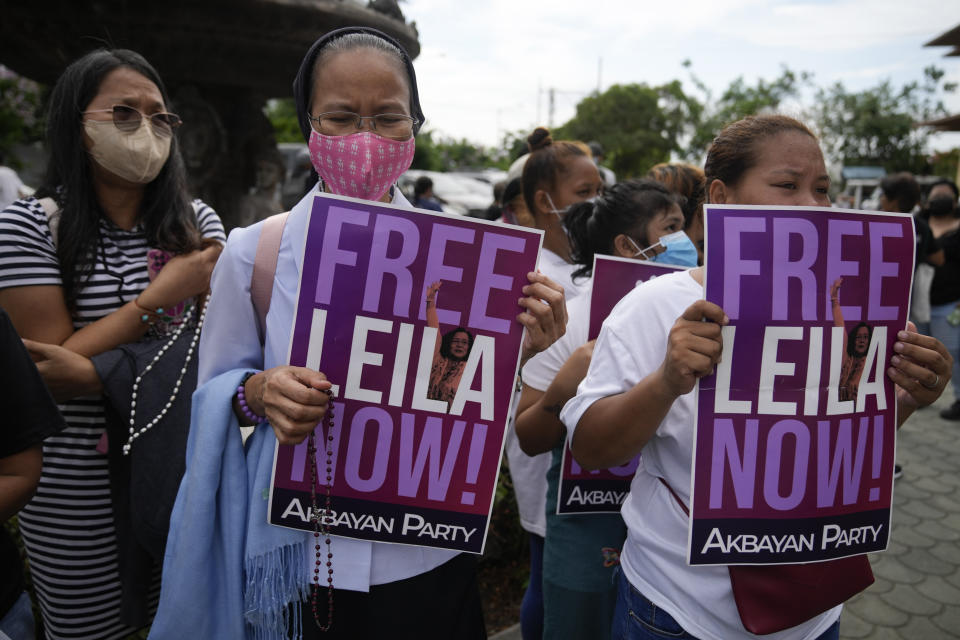 Supporters of detained former opposition Senator Leila de Lima pray as they hold slogans outside the Muntinlupa trial court on Friday, May 12, 2023 in Muntinlupa, Philippines. De Lima was acquitted by the Muntinlupa court in one of her drug related charges she says were fabricated by former President Rodrigo Duterte and his officials in an attempt to muzzle her criticism of his deadly crackdown on illegal drugs. (AP Photo/Aaron Favila)