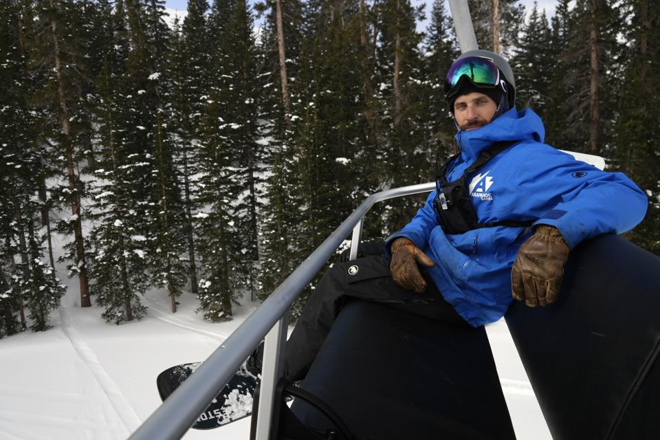 Mike Nathan, sustainability manager at Arapahoe Basin Ski Area, rides a lift Friday, Jan. 20, 2023, in Dillon, Colo. Earlier this year, Nathan and other industry leaders met with the staff of Colorado’s governor to encourage the rapid transition to manufacturing EV heavy machinery statewide. (AP Photo/Brittany Peterson)