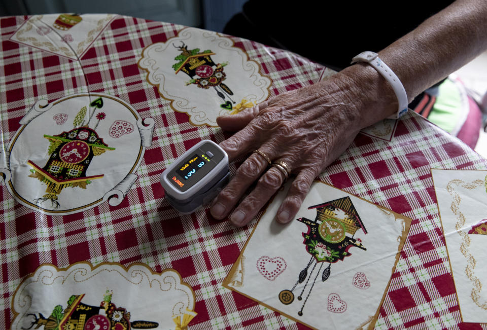 Doctor Mauro Morganti checks a patient's oxygen saturation level with a pulse oximeter during a house call, in Tartano, near Sondrio, Italy, Tuesday, Dec. 1, 2020. (AP Photo/Antonio Calanni)
