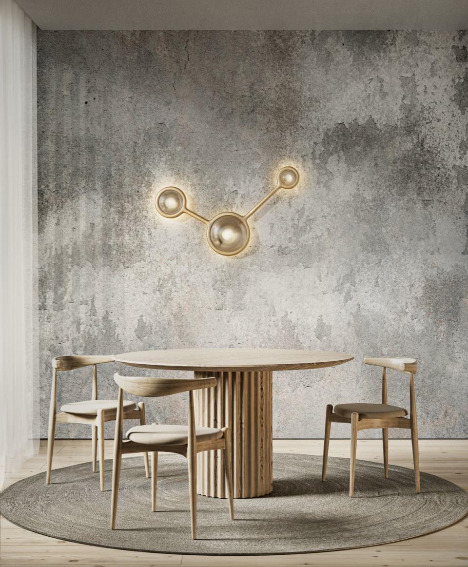 a dining table and chairs in front of a gold wall sconce