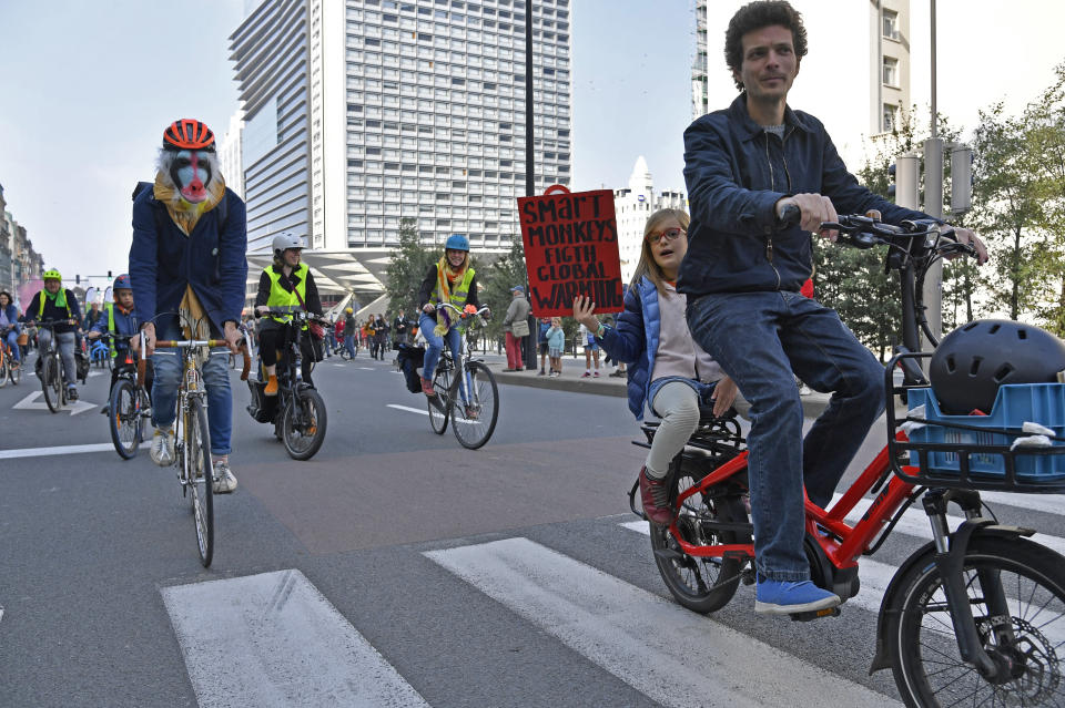 A small girl holds a sign as she rides on the back of a bicycle during a climate demonstration and march in Brussels, Sunday, Oct. 10, 2021. Some 80 organizations are joining in a climate march through Brussels to demand change and push politicians to effective action in Glasgow later this month.(AP Photo/Geert Vanden Wijngaert)