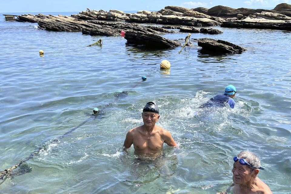 Lu Chuan-hsiong, center, swims along the coast near Keelung in Taiwan, Thursday, Aug. 4, 2022. Lu, 63, who was enjoying his morning swim, says he wasn't worried about the recent China and Taiwan tensions. "Because Taiwanese and Chinese, we're all one family. There's a lot of mainlanders here, too," he said. (AP Photo/Johnson Lai)
