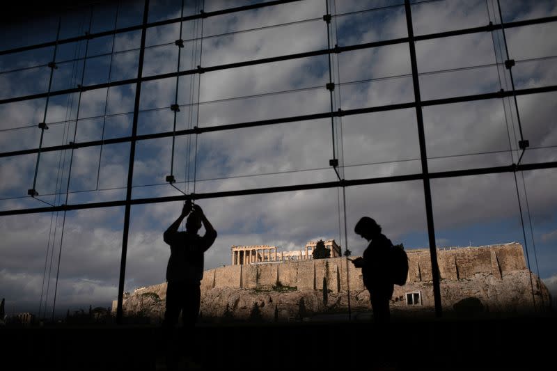 Visitors take pictures of the Parthenon temple seen in the background, as they visit the Parthenon Gallery of the Acropolis Museum, in Athens