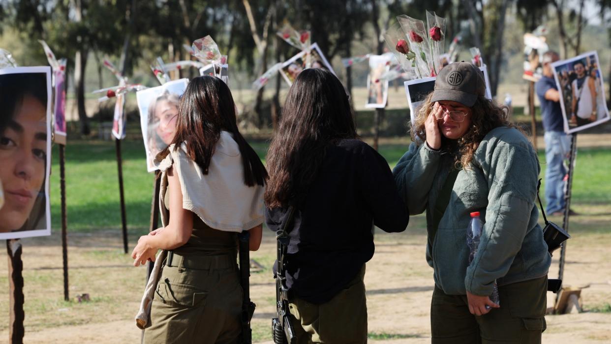  An Israeli soldier wipes her tears as she stands with fellow troops in front of pictures of people taken captive or killed by Hamas militants during the Supernova music festival on October 7. 