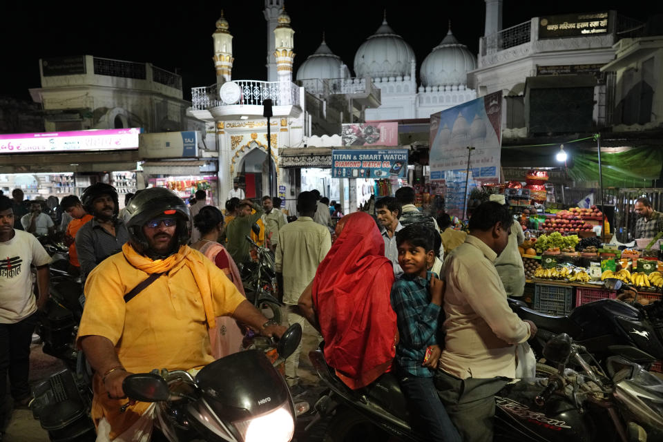Hindus and Muslims shop outside a Mosque in the evening, in Ayodhya, India, March 28, 2023. India, a country of more than 1.4 billion people is on the cusp of becoming the world's most populated nation. But most of the Hindus and Muslims embody the opposing sides of a deeply entrenched religious divide that presents India one of its biggest challenges so far: to safeguard freedoms to its Muslim minority at a time when a rising tide of Hindu nationalism is laying waste to the country's secular underpinnings.(AP Photo/Manish Swarup)