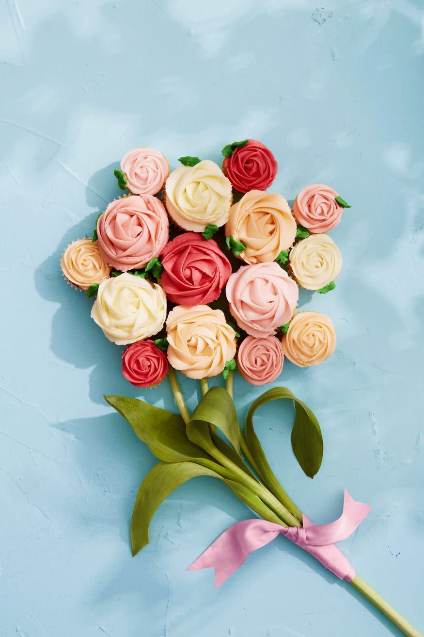 vanilla cream cupcakes with frosting piped to look like roses and cupcakes arranged in the shape of a bouquet with real flower stems next to them