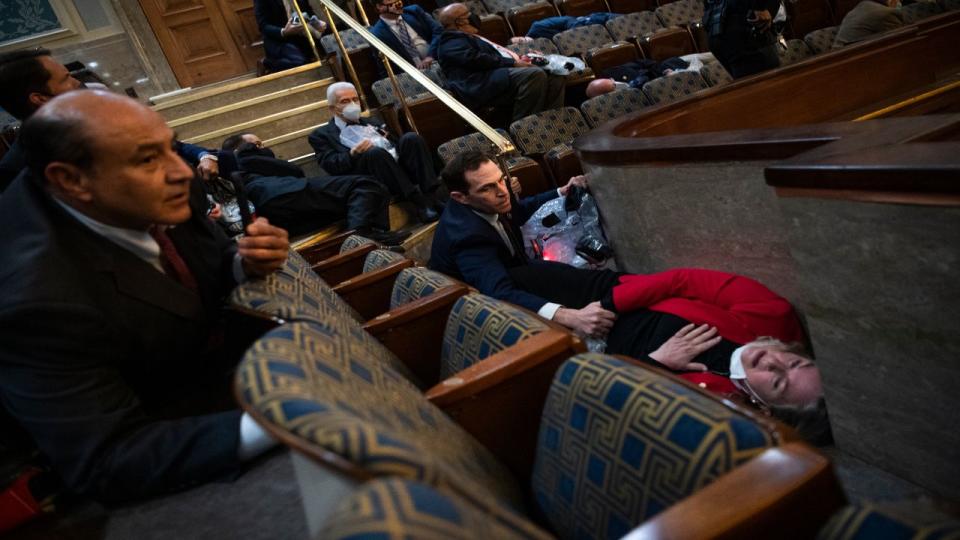 UNITED STATES - JANUARY 6: Rep. Jason Crow, D-Colo.,  comforts Rep. Susan Wild, D-Pa., while taking cover as protesters disrupt the joint session of Congress to certify the Electoral College vote on Wednesday, January 6, 2021.