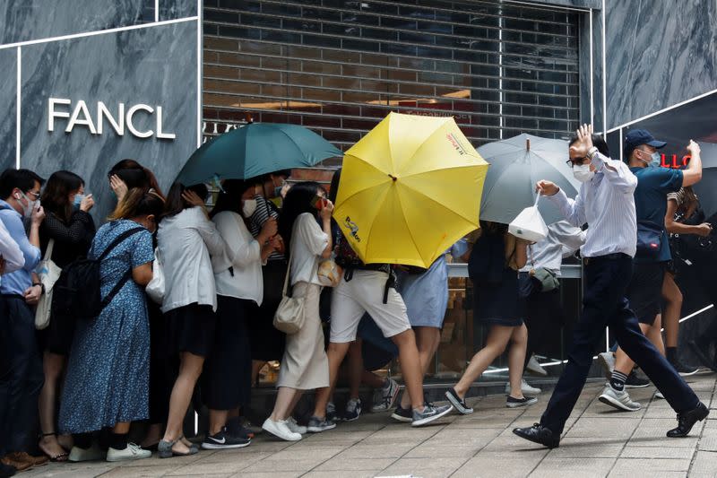 People take cover as riot police use pepper spray projectile during a protest at Central District, as a second reading of a controversial national anthem law takes place in Hong Kong