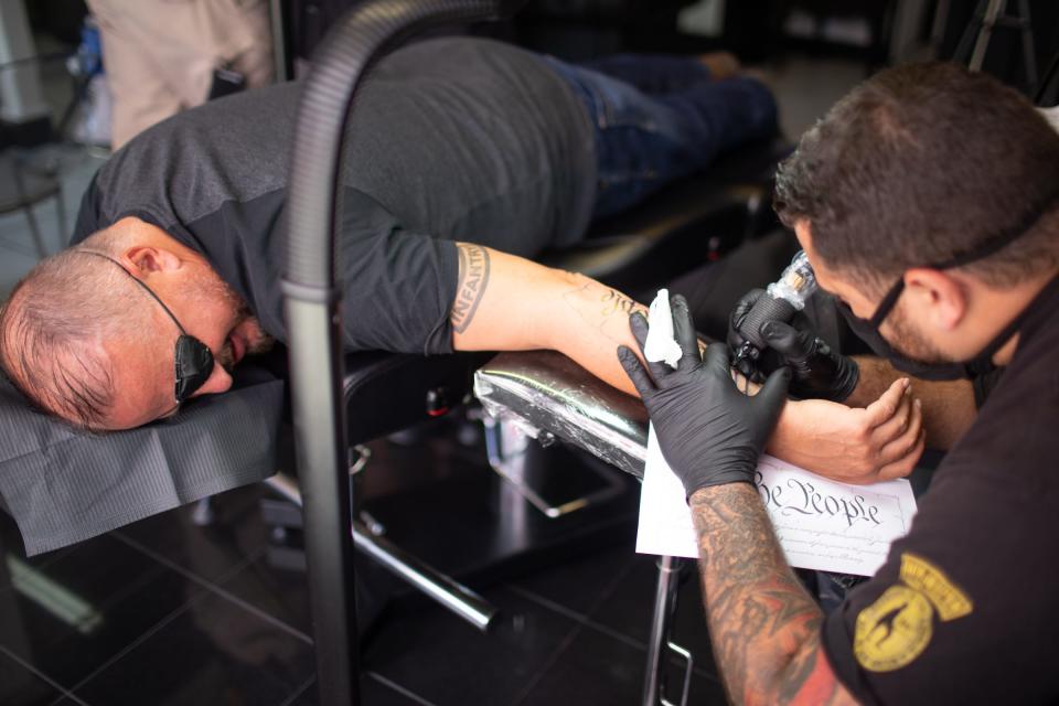 Oath Keeper President Stewart Rhodes, left, is tattooed by Roberto Minuta at his shop.