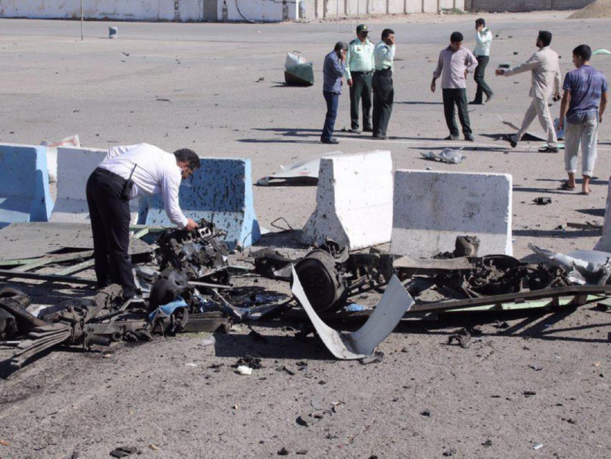 An officer inspects the vehicle wreckage outside a police station: AFP/Getty