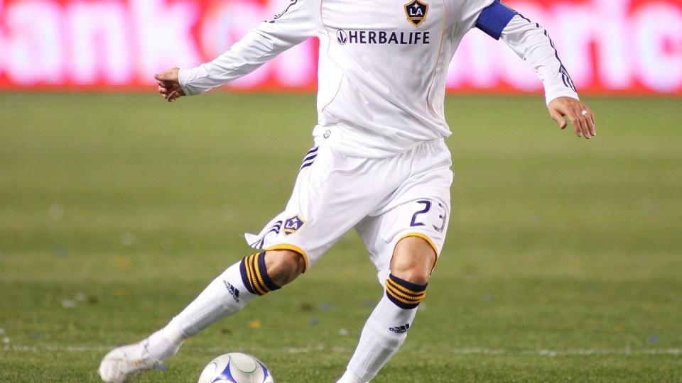 david beckham wearing a white uniform and kicking a soccer ball during a match