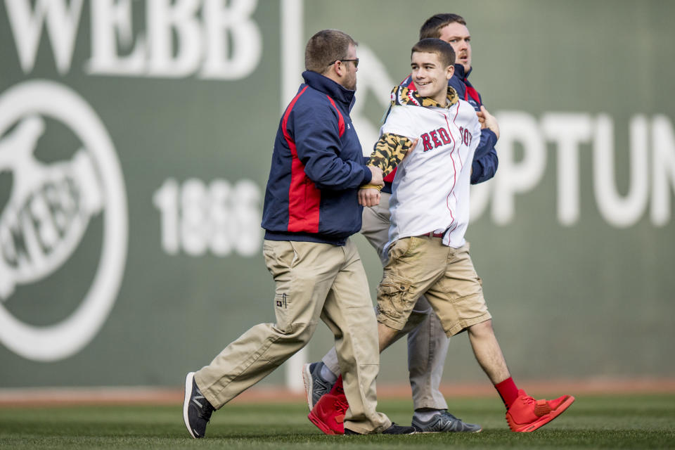 A fan is escorted by security members after running onto the field during the eighth inning of the Boston Red Sox home opener against the Pittsburgh Pirates April 3, 2017 at Fenway Park in Boston, Massachusetts. (Photo by Billie Weiss/Boston Red Sox/Getty Images)