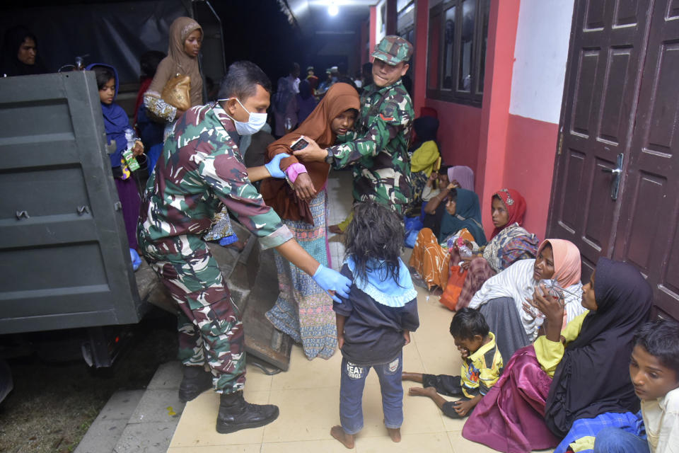 Indonesian soldiers help ethnic Rohingya women and children to step out of a military truck upon arrival at a temporary shelter after their boat landed in Pidie, Aceh province, Indonesia, Monday, Dec. 26, 2022. A second group in two days of weak and exhausted Rohingya Muslims landed on a beach in Indonesia's northernmost province of Aceh on Monday after weeks at sea, officials said. (AP Photo/Rahmat Mirza)