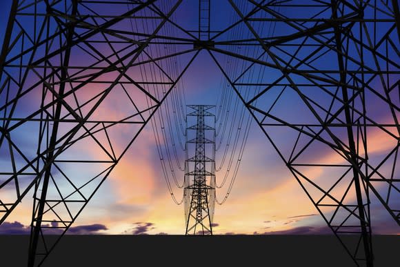 High-transmission power lines and towers near sunset.