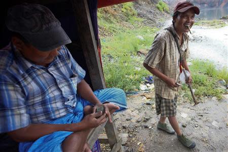 Tin Tun (R), a 38-year-old jade hand-picker, sells the jade which he found after searching the whole night at a jade mine in Hpakant township, Kachin State July 8, 2013. REUTERS/Minzayar