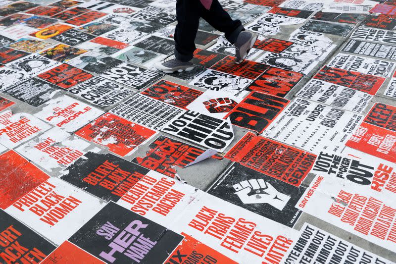 A person walks over BLM posters at Black Lives Matter Plaza in Washington