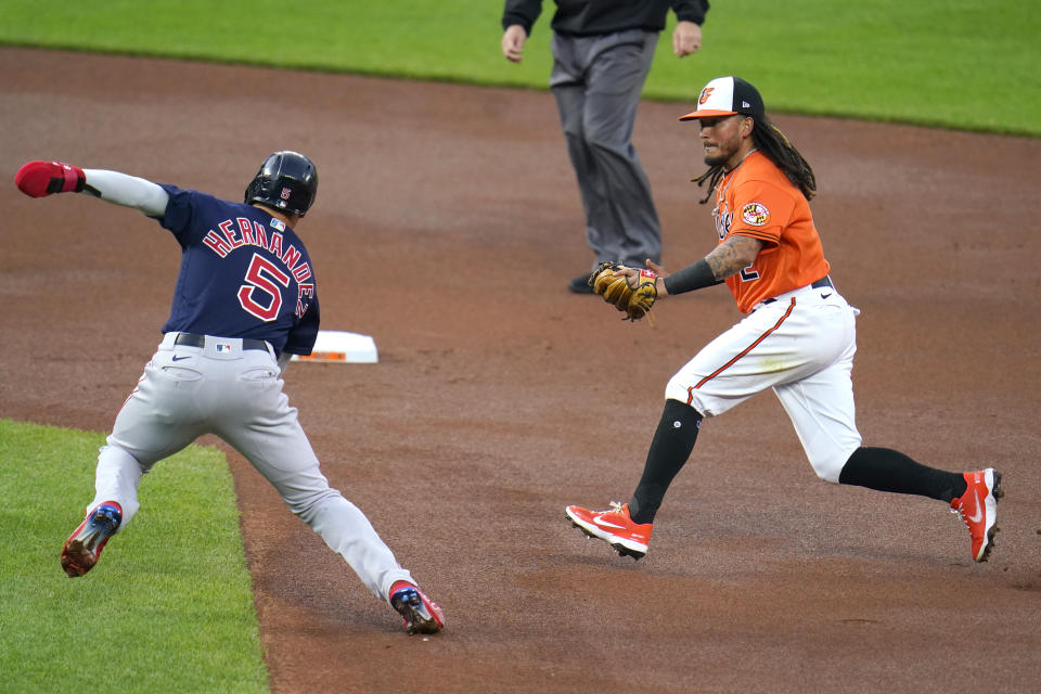 Baltimore Orioles shortstop Freddy Galvis, right, runs to tag out Boston Red Sox's Enrique Hernandez, left, on a fielders choice ground ball by Red Sox's Alex Verdugo during the first inning of a baseball game, Saturday, April 10, 2021, in Baltimore. (AP Photo/Julio Cortez)