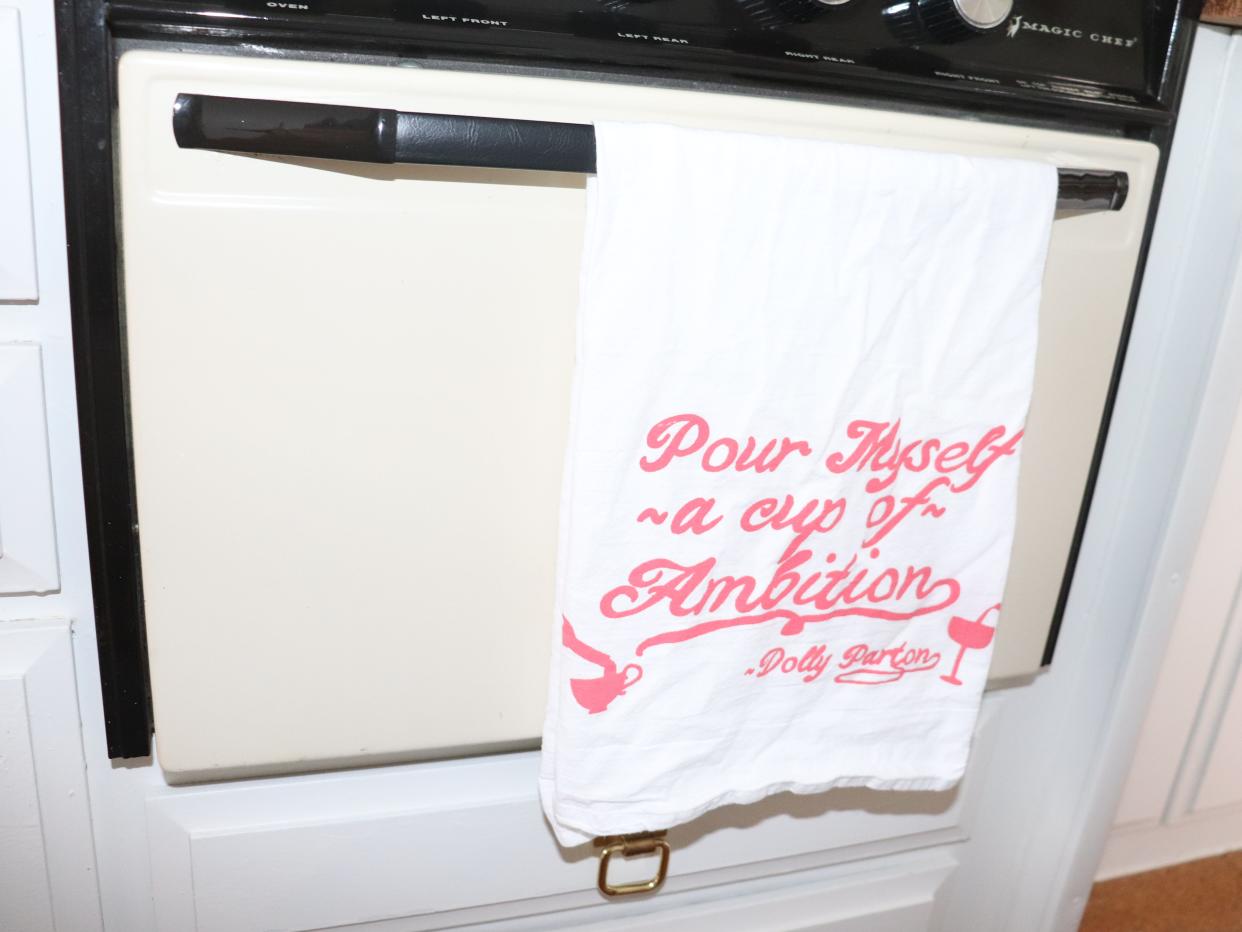 A kitchen towel that reads "Pour myself a cup of ambition"