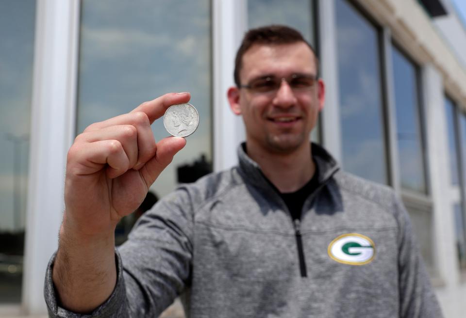 George Lepak, owner of Allouez Rare Coin, holds a Peace Silver Dollar while standing outside the store's new location at 533 E. Walnut St. in downtown Green Bay.