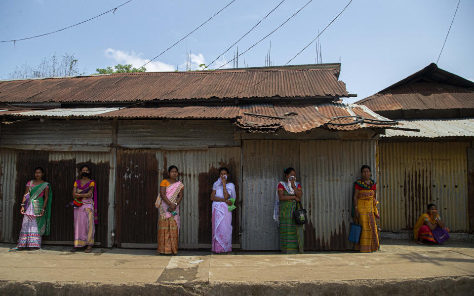 Indian tribal women stand in a queue outside a grocery shop during the nationwide lockdown at Daranggiri village, west of Gauhati, India, Monday, April 20, 2020. India recorded its biggest single-day spike in coronavirus cases on Monday as the government eased one of the world's strictest lockdowns to allow some manufacturing and agricultural activity to resume. (AP Photo/Anupam Nath)