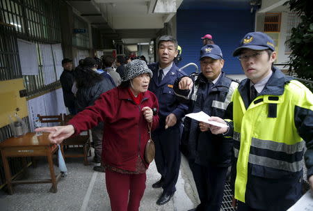 Policemen assist a voter at a polling station during general elections in Taipei, Taiwan January 16, 2016. REUTERS/Damir Sagolj