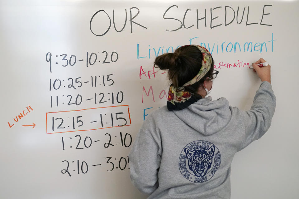 Global history teacher Alis Anasol writes the schedule on a white board in her classroom at West Brooklyn Community High School, Thursday, Oct. 29, 2020, in New York. The high school is a "transfer school," catering to students who haven't done well elsewhere, giving them a chance to graduate and succeed. The school is partnered with Good Shepherd Services, who provides advocate counselors to help students achieve their goals. The school, which recently reopened, was forced to shut down for three weeks due to a spike in coronavirus cases in the neighborhood. (AP Photo/Kathy Willens)