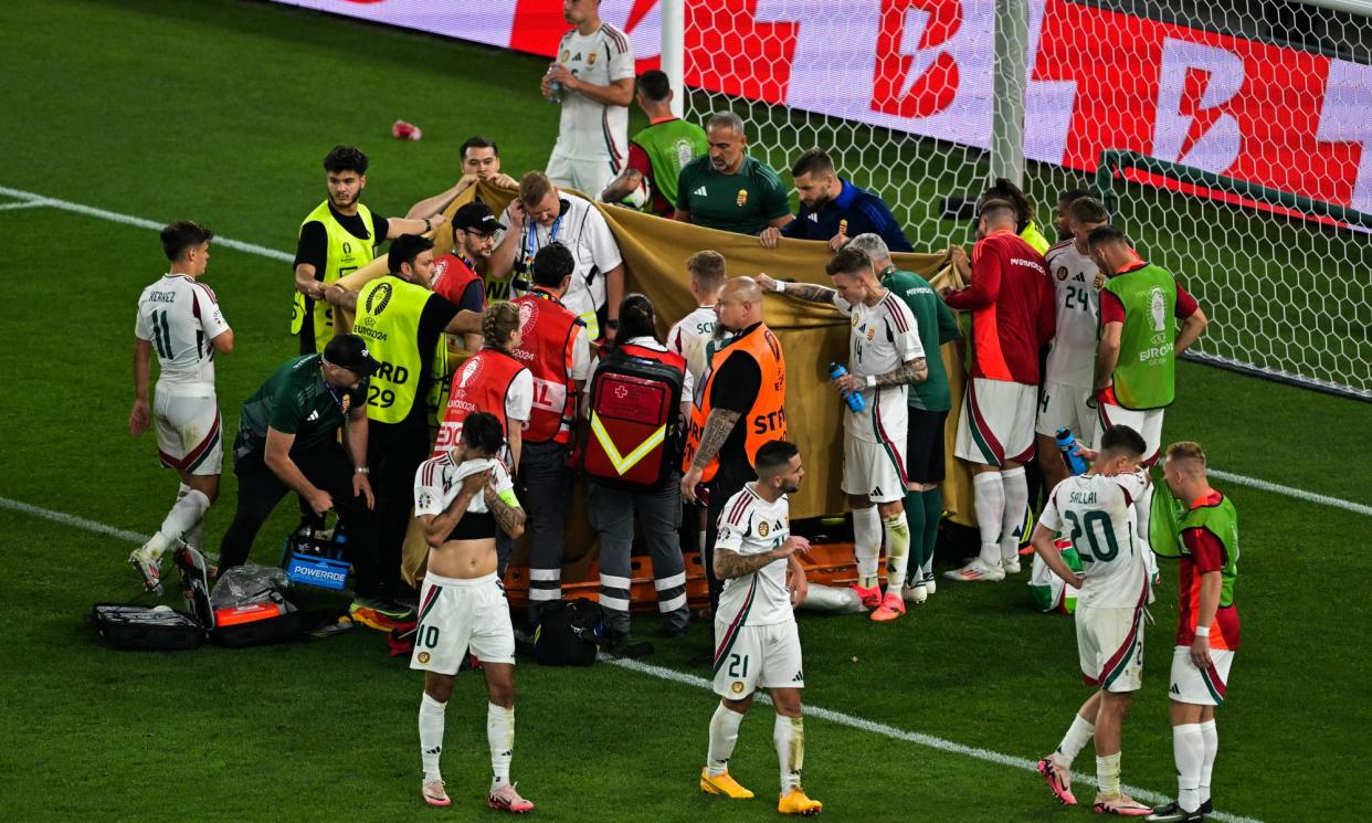 <span>Players and stewards hold sheeting to cover Barnabas Varga.</span><span>Photograph: Damien Meyer/AFP/Getty Images</span>