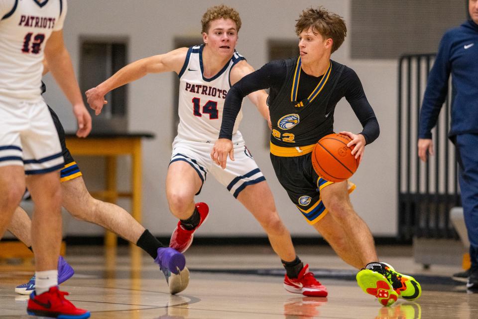 Evansville Christian High School senior Josiah Dunham (22) drives the ball around the defense of Heritage Hills High School sophomore Peyton Gray (14) during the first half of a varsity game in the SNKRS4SANTA Shootout, Saturday, Dec. 2, 2023, at Brownsburg High School.