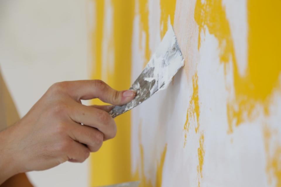 Applying skim coat on yellow wall