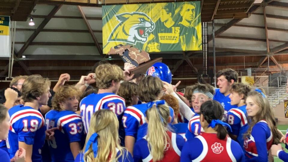 Lenawee Christian celebrates with the state championship trophy after defeating Suttons Bay, 31-20, in the Division 1 8-man state title game at the Superior Dome in Marquette.