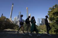 People hike through New York's Central Park with the Central Park Tower, center, behind them, Tuesday, Sept. 17, 2019. At 1550 feet (472 meters) the tower is the world's tallest residential apartment building, according to the developer, Extell Development Co. (AP Photo/Mark Lennihan)