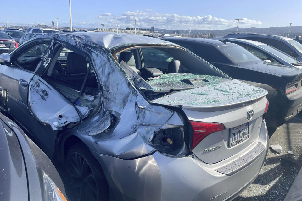 A damaged car is seen in an on-airport employee parking lot after tire debris from a Boeing 777 landed on it at San Francisco International Airport, Thursday, March 7, 2024. A United Airlines jetliner bound for Japan made a safe landing in Los Angeles on Thursday after losing a tire while taking off from San Francisco. (AP Photo/Haven Daley)