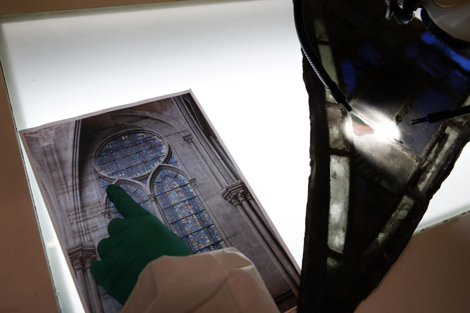 In this photo taken on Wednesday, Oct. 9, 2019, Glass specialist Claudine Loisel checks the Notre Dame cathedral's stained-glass windows in a lab at Champs-sur-Marne, west of Paris. Scientists at the French government's Historical Monuments Research Laboratory are using these objects as clues in an urgent and vital task, working out how to safely restore the beloved Paris cathedral and identify what perils remain inside in a race against the clock. (AP Photo/Francois Mori)