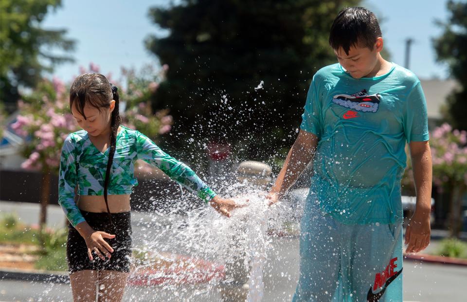 (7/7/21) Six-year-old Andrea Ramirez, left, and her 10-year-old Brother Frederick Ramirez play in the cooling jets of water at the splash pad at Valverde Park in Lathrop. CLIFFORD OTO/THE STOCKTON RECORD