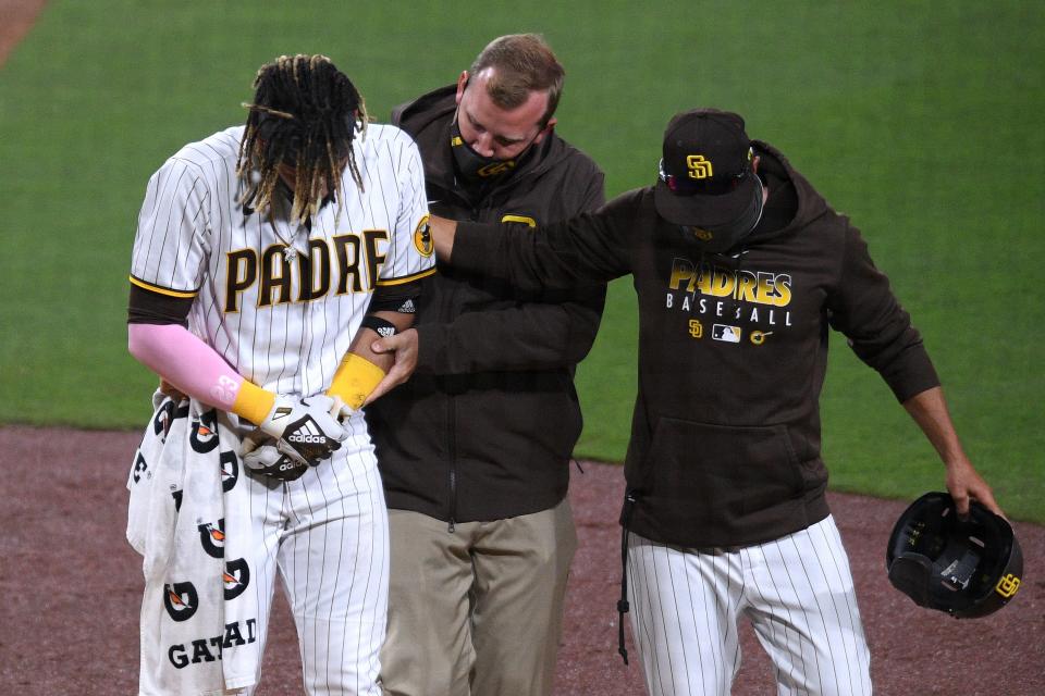 Fernando Tatis Jr. is helped off the field by a trainer and manager Jayce Tingler after injuring his shoulder.