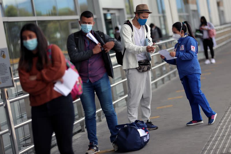 Foto de archivo. Un empleado de la Cruz Roja con una máscara facial habla con un pasajero, después de que el Gobierno de Cclombia autorizó reactivar los vuelos internacionales, en medio de la pandemia de coronavirus, en Bogotá