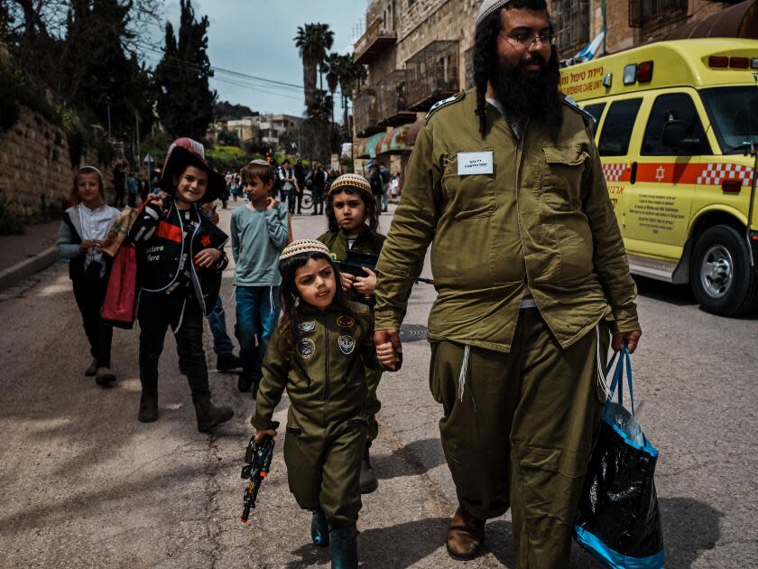 Yonatan Ler holds his son Nave’s hand while his other son, Mayon, follows. The family dressed in military costumes for a Purim parade in Hebron in the West Bank.